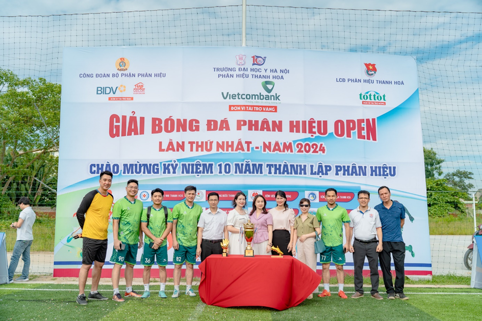 A group of people standing in front of a banner

Description automatically generated